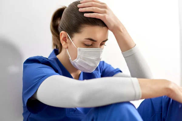 Trauriger Arzt oder Krankenschwester mit Mundschutz am Kopf — Stockfoto