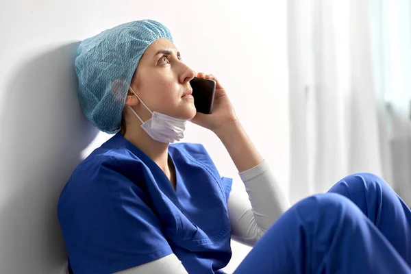 Trauriger Arzt oder Krankenschwester telefoniert mit dem Smartphone — Stockfoto