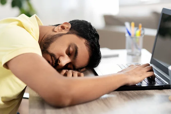 Homem indiano dormindo na mesa com laptop em casa — Fotografia de Stock