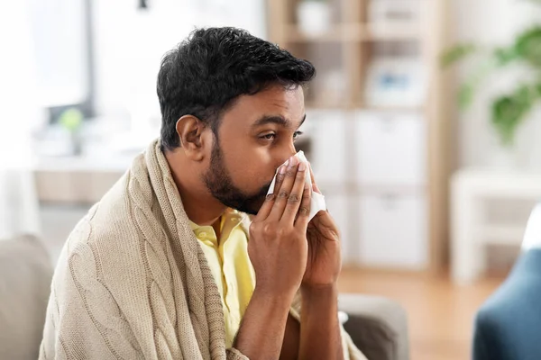 Nemocný muž foukání nos v papírové tkáni doma — Stock fotografie