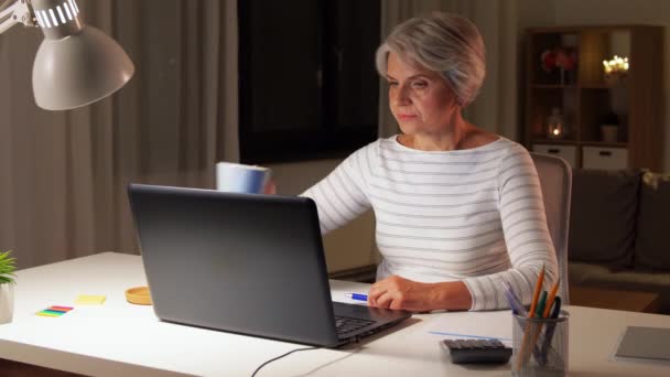 Wanita senior dengan laptop minum kopi di rumah — Stok Video