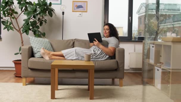 집 소파에 태블릿 PC 컴퓨터를 가지고 있는 여성 — 비디오