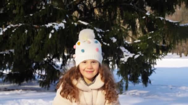 Feliz niña lanzando nieve en el parque de invierno — Vídeos de Stock