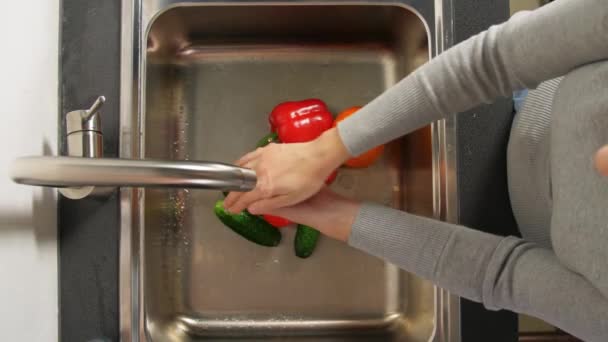 Жінка миє фрукти та овочі на кухні — стокове відео