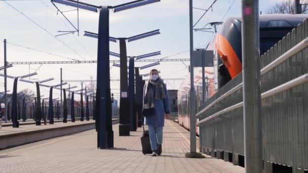 Kvinna i ansiktet mask promenader längs järnvägsplattform — Stockvideo