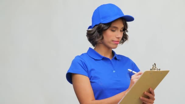 Happy delivery girl with clipboard and pen writing — Stock Video