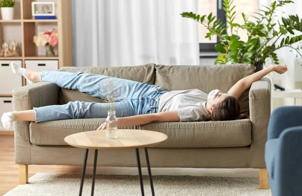 Femme malade dans le masque médical couché sur le canapé à la maison — Photo