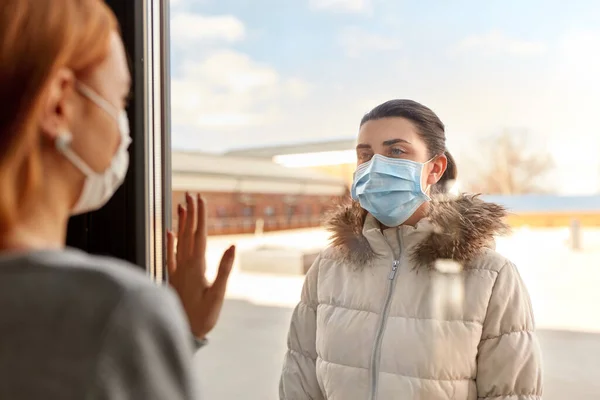 Donna in maschera cercando di amico attraverso la finestra — Foto Stock