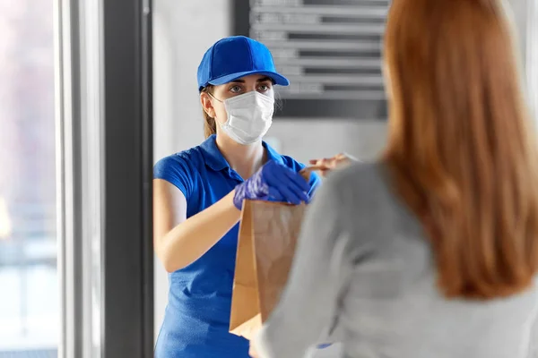 Entrega chica en máscara dando bolsa de papel a la mujer — Foto de Stock