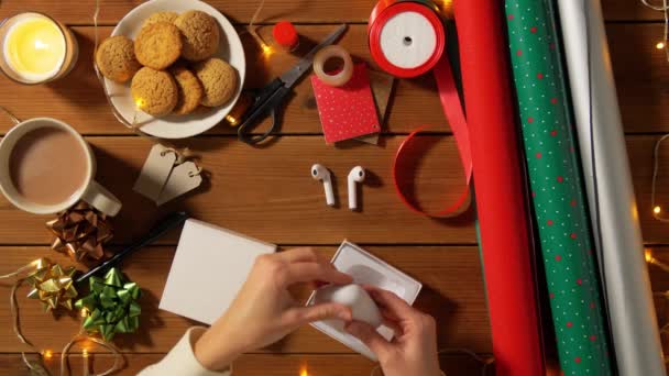 Женщина обертывает наушники на рождественский подарок — стоковое видео
