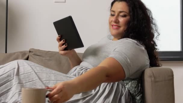 Frau mit Tablet-PC trinkt Kaffee zu Hause — Stockvideo