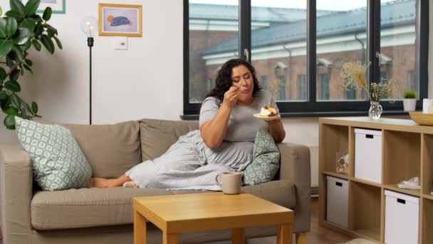 Kvinna dricka te och äta tårta hemma — Stockvideo
