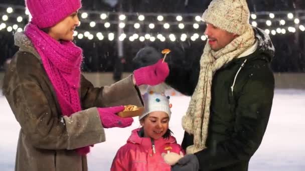 Boldog család eszik palacsintát korcsolyapályán — Stock videók