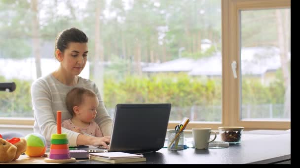 Mother with baby working on laptop at home office — Stock Video