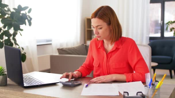 Žena s kalkulačkou a papíry pracuje doma — Stock video