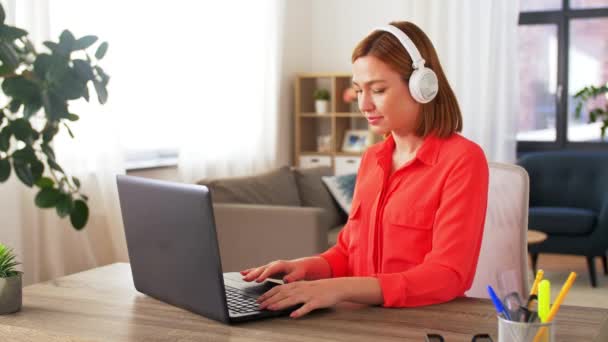 Mujer en auriculares con portátil trabajando en casa — Vídeo de stock