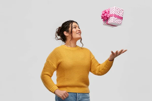 Sonriente joven mujer lanzando caja de regalo —  Fotos de Stock