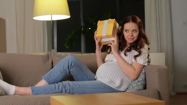 Curious pregnant woman with gift box at home — Stock Video