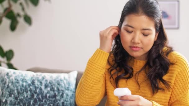 Mulher asiática com fones de ouvido e smartphone em casa — Vídeo de Stock