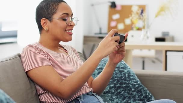 Счастливая женщина играет в игру на смартфоне дома — стоковое видео
