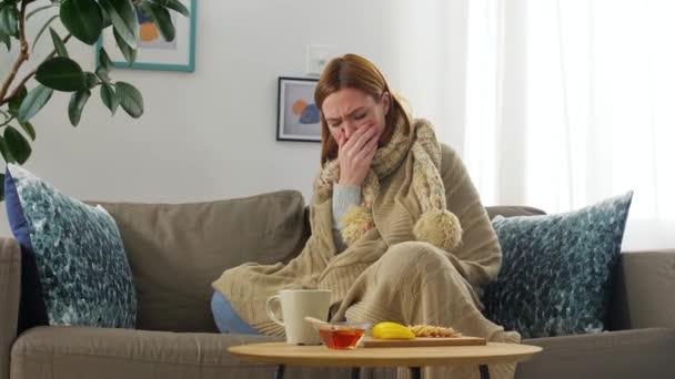 Грустная больная молодая женщина пьет горячий чай дома — стоковое видео