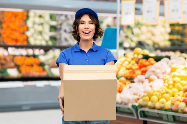 Happy delivery girl with box at grocery store — Stock Photo, Image