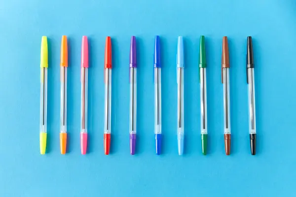 Fila de plumas multicolores sobre fondo azul —  Fotos de Stock