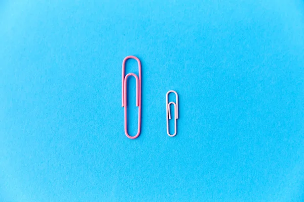 Pink office clips on blue background — Stock Photo, Image