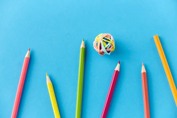 Crayons à colorier et élastiques sur fond bleu — Photo