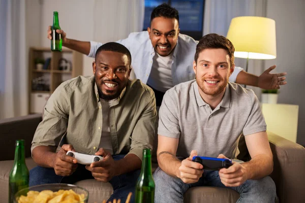 Amici felici che giocano ai videogiochi a casa di notte — Foto Stock