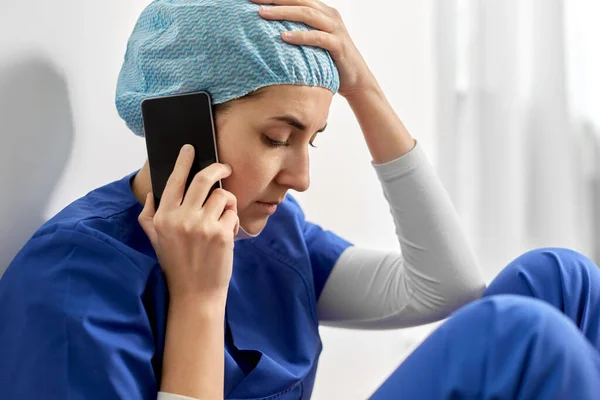 Triste médico o enfermera llamando en el teléfono inteligente —  Fotos de Stock