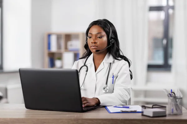 Medico africano con auricolare e laptop in ospedale — Foto Stock