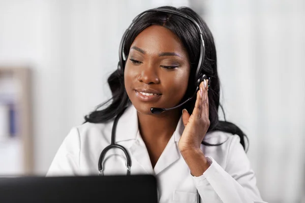 Afrikanischer Arzt mit Kopfhörer und Laptop im Krankenhaus — Stockfoto