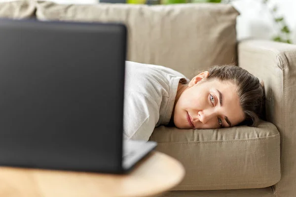 Unatkozó nő laptoppal heverő kanapén otthon — Stock Fotó