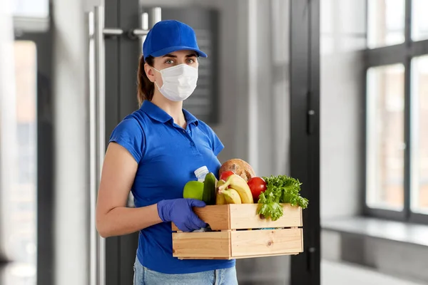 Mulher entrega na máscara facial com comida na caixa — Fotografia de Stock