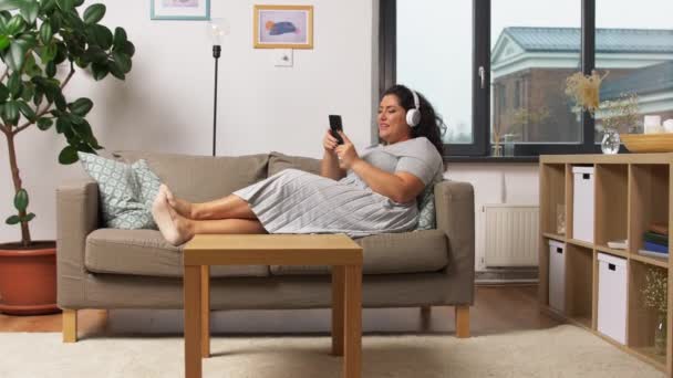 Kobieta w słuchawkach słucha muzyki na smartfonie — Wideo stockowe