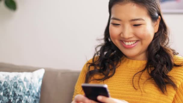 Sonriente asiático mujer con smartphone en casa — Vídeo de stock