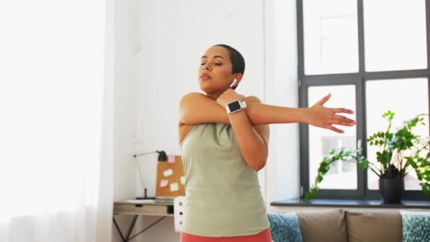 Mujer con reloj inteligente brazo de estiramiento en casa — Vídeos de Stock