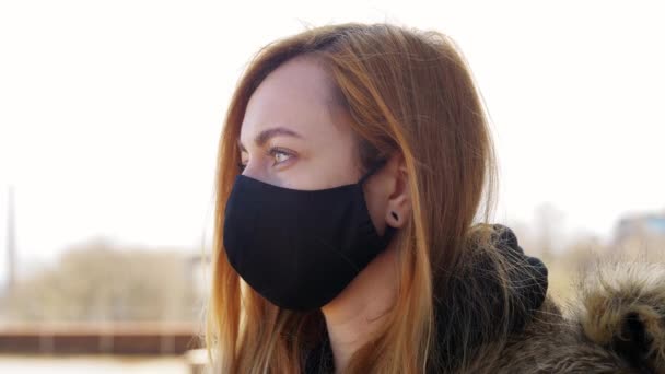 Женщина носит защитную многоразовую барьерную маску — стоковое видео