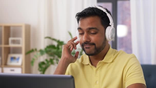 Hombre en auriculares con portátil trabajando en casa — Vídeo de stock