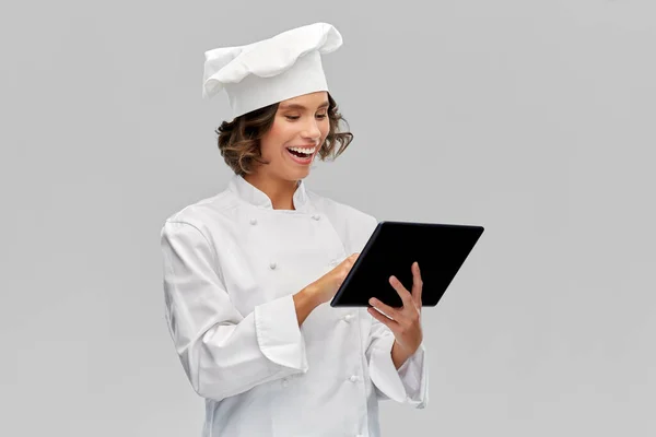 Улыбающаяся шеф-повар в токе с планшетным компьютером — стоковое фото