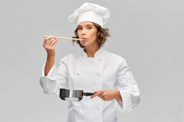 Vrouwelijke chef met steelpan proeverij voedsel — Stockfoto