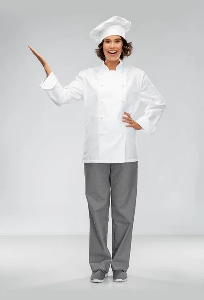 Улыбающаяся женщина-шеф-повар держит что-то под рукой — стоковое фото
