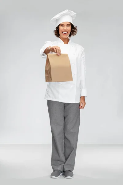 Chef feminino feliz com comida takeaway em saco de papel — Fotografia de Stock