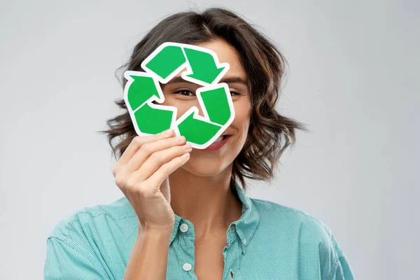 Улыбающаяся женщина смотрит через зеленый знак переработки — стоковое фото