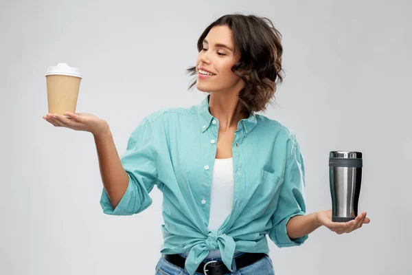 Mujer que compara la taza termo y taza de café de papel — Foto de Stock