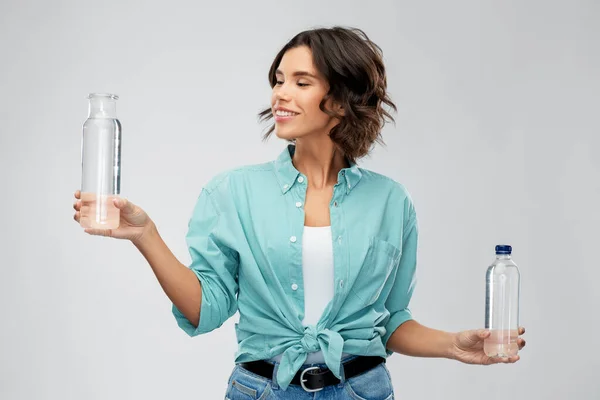 Sonriente joven mujer comparando botellas de agua — Foto de Stock