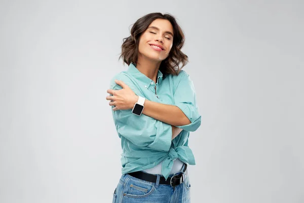 Mulher sorridente com relógio inteligente abraçando-se — Fotografia de Stock