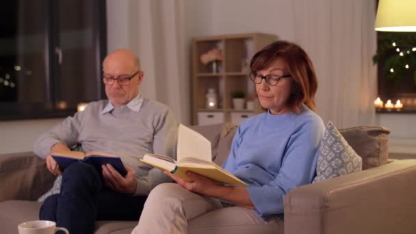 Feliz pareja de ancianos leyendo libros en casa — Vídeos de Stock