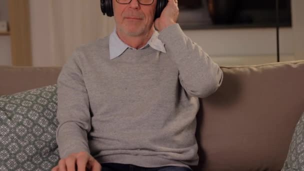 Öreg ember fülhallgató hallgat zenét otthon — Stock videók